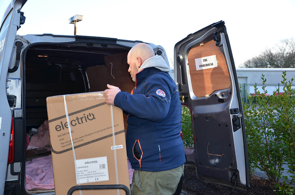 Man loading white goods into the back of a van