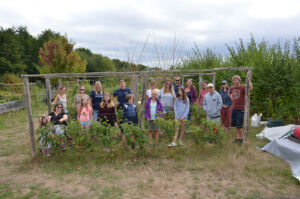 Adults and children standing behind garden trellis and smiling