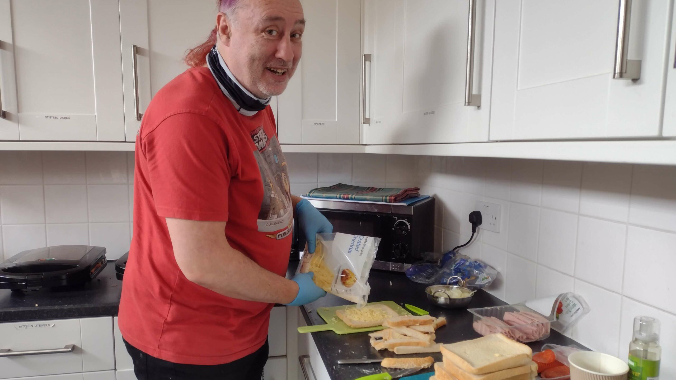 A man smiling while making cheese toasties