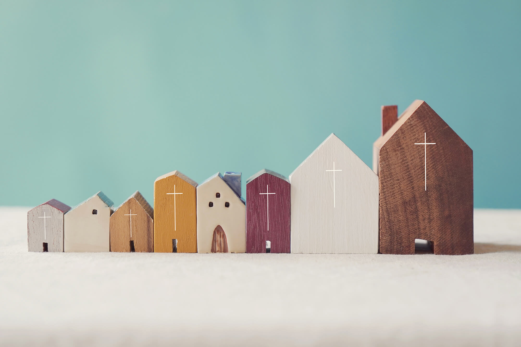 A row of model wooden churches on a pale blue background