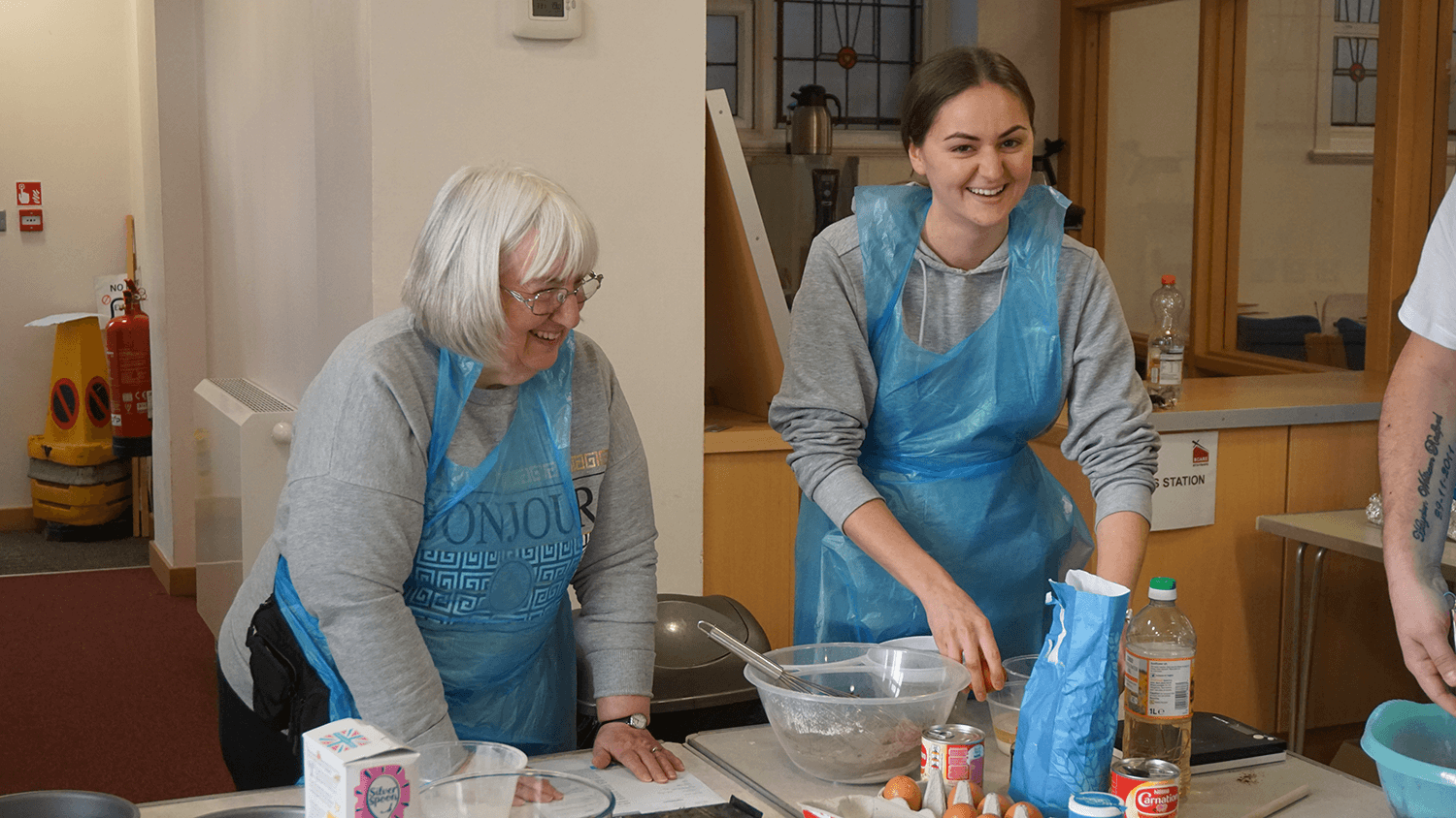 Two women baking and smiling at the camera