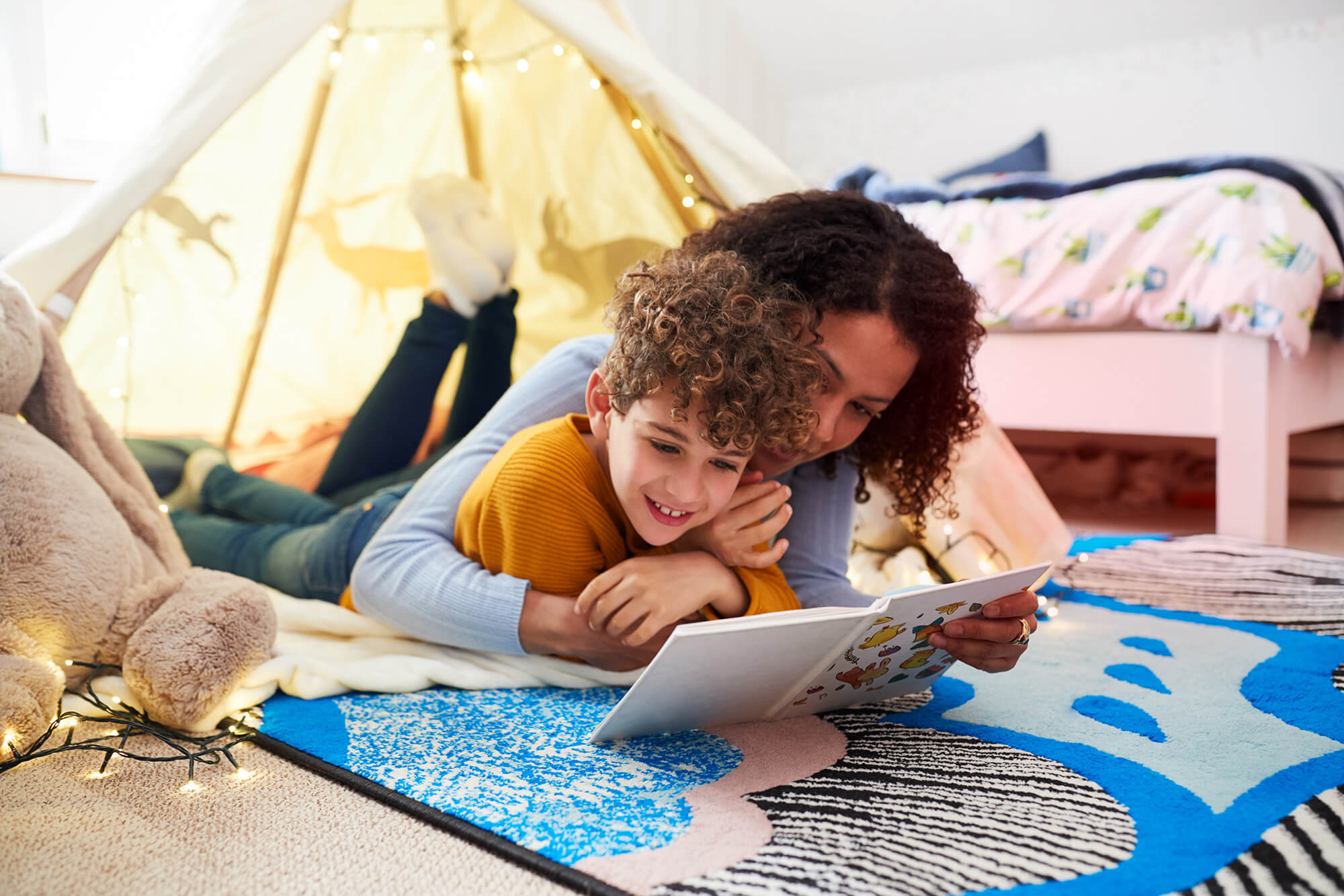 Woman lying on the floor, reading book to child