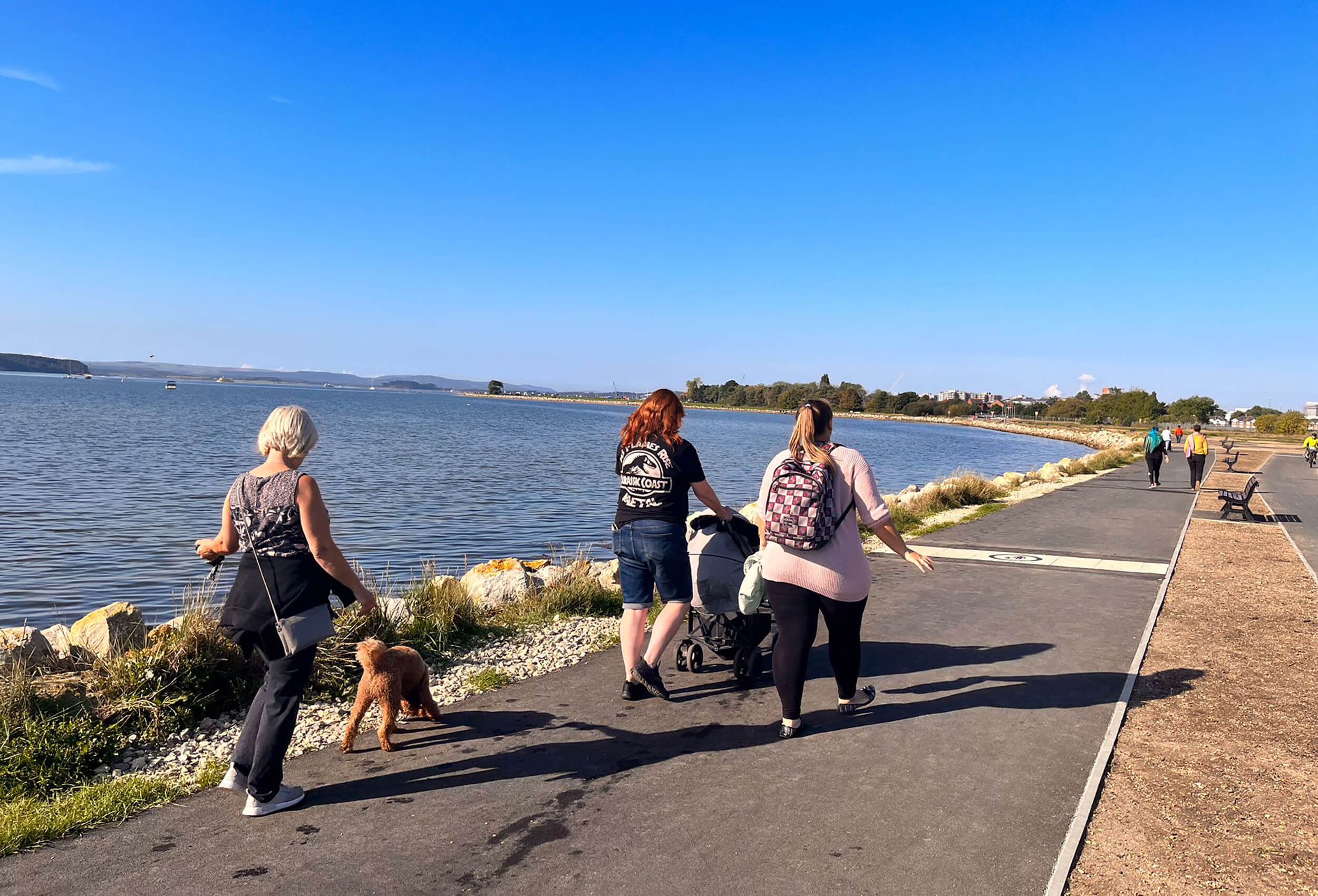 Three women and a dog walk along the promenade