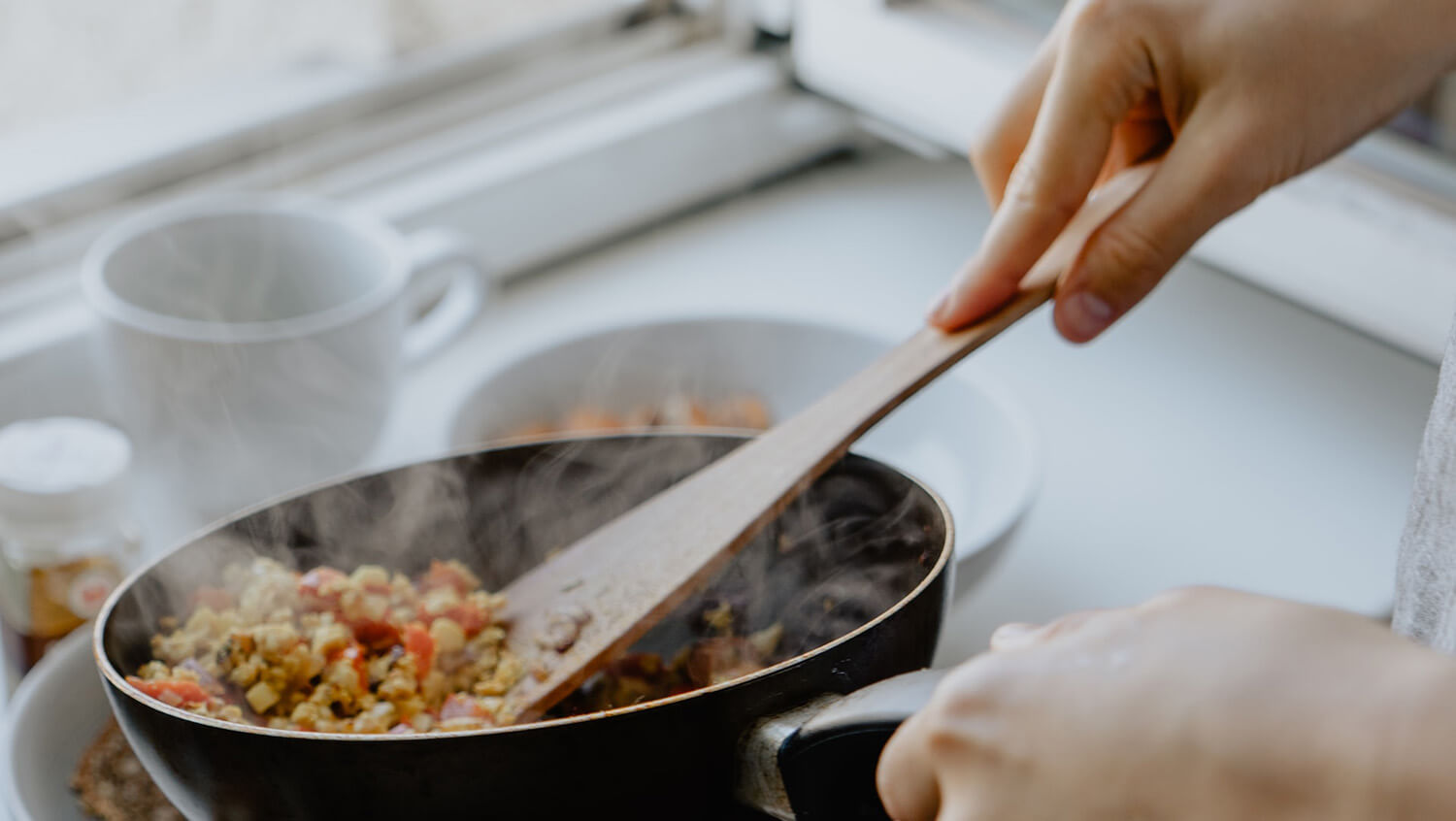 Close up of hands dishing up a hot meal from a frying pan