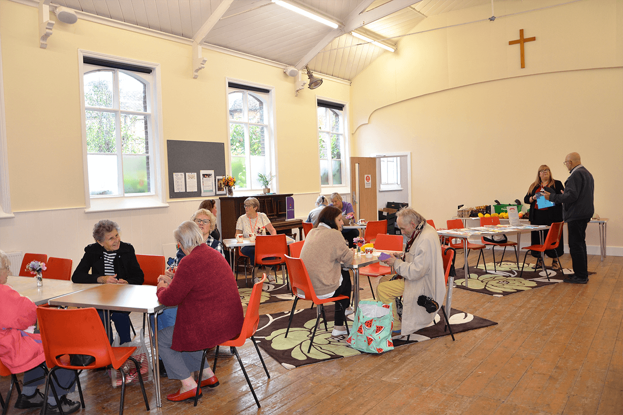 A church hall with people sat around tables and chatting