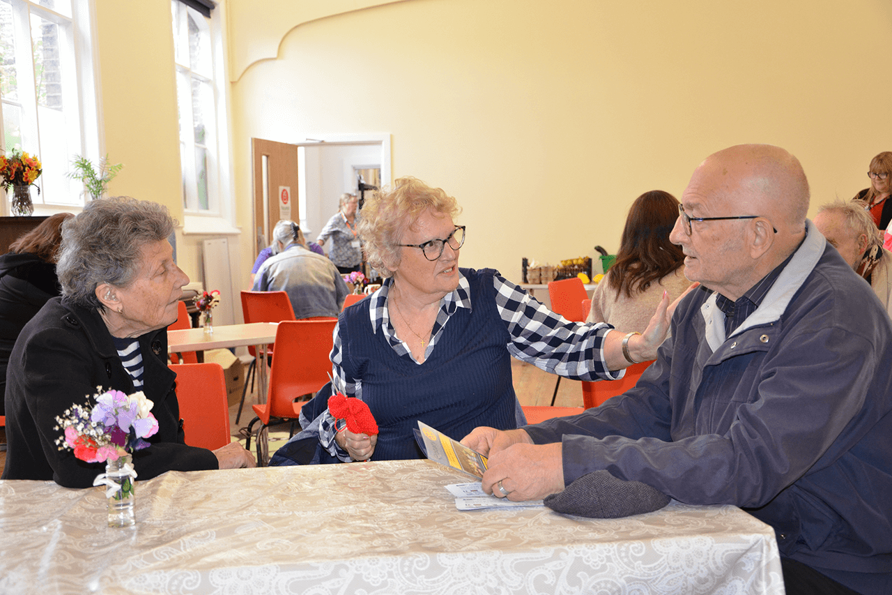 Two women and a man sit around a table chatting