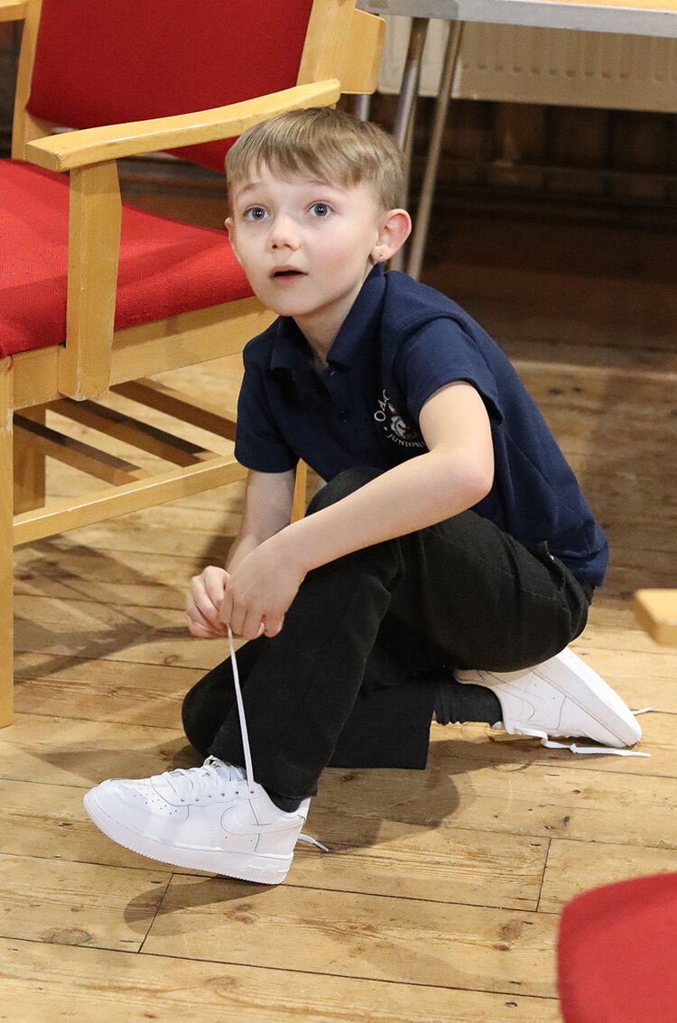 A young boy puts on new trainers while crouched on the floor