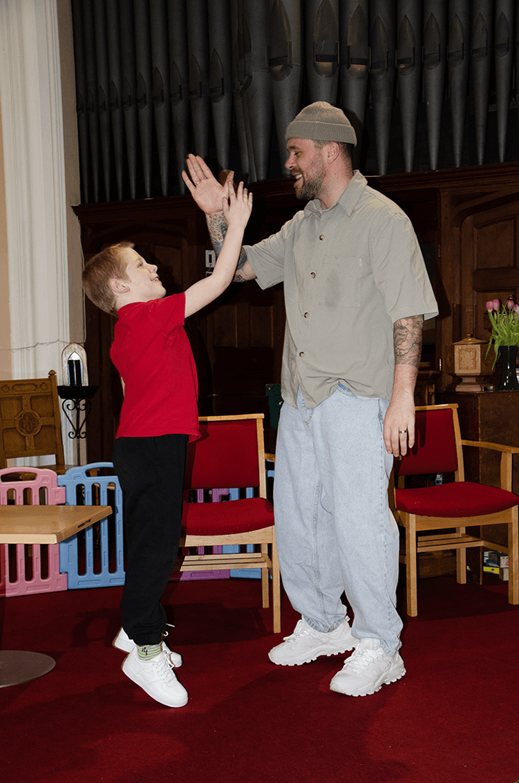 Harrison from Blue Soul Customs high fives with a young boy from the SMILE Lone Parent Families project