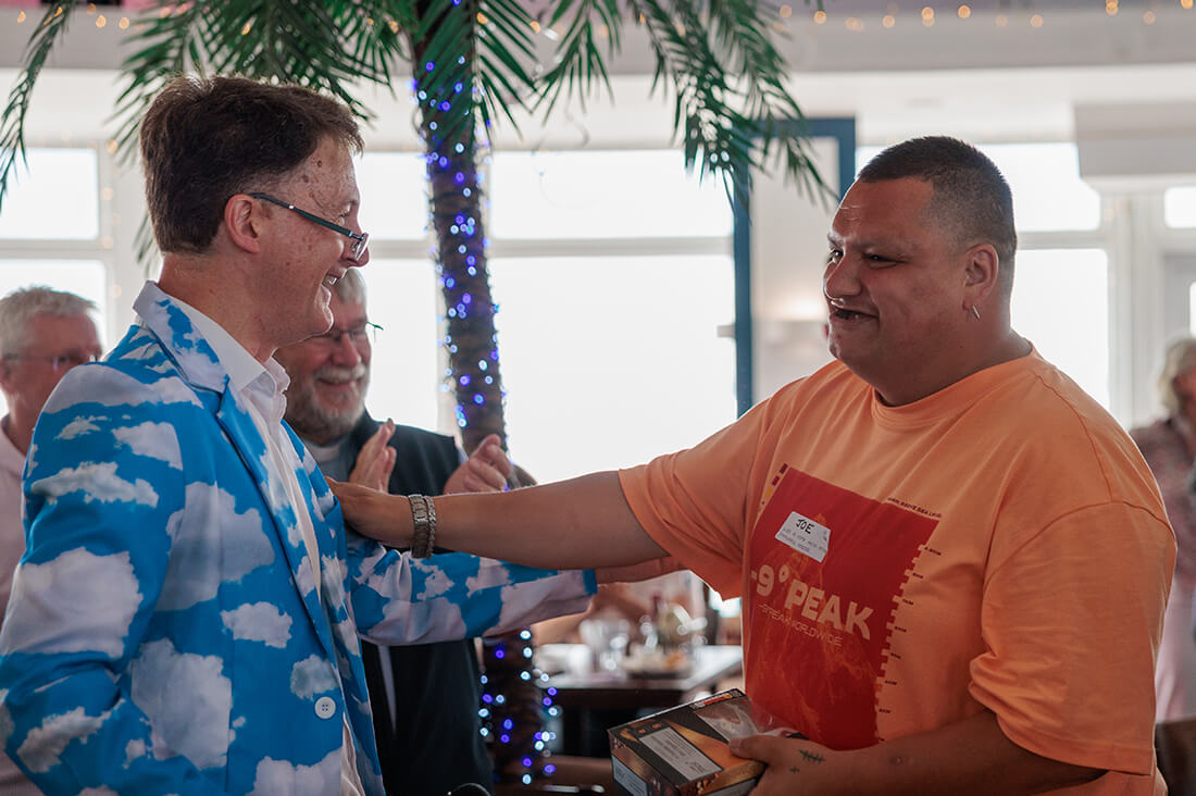 Two men stand smiling at each other and with their arms reaching out to each other