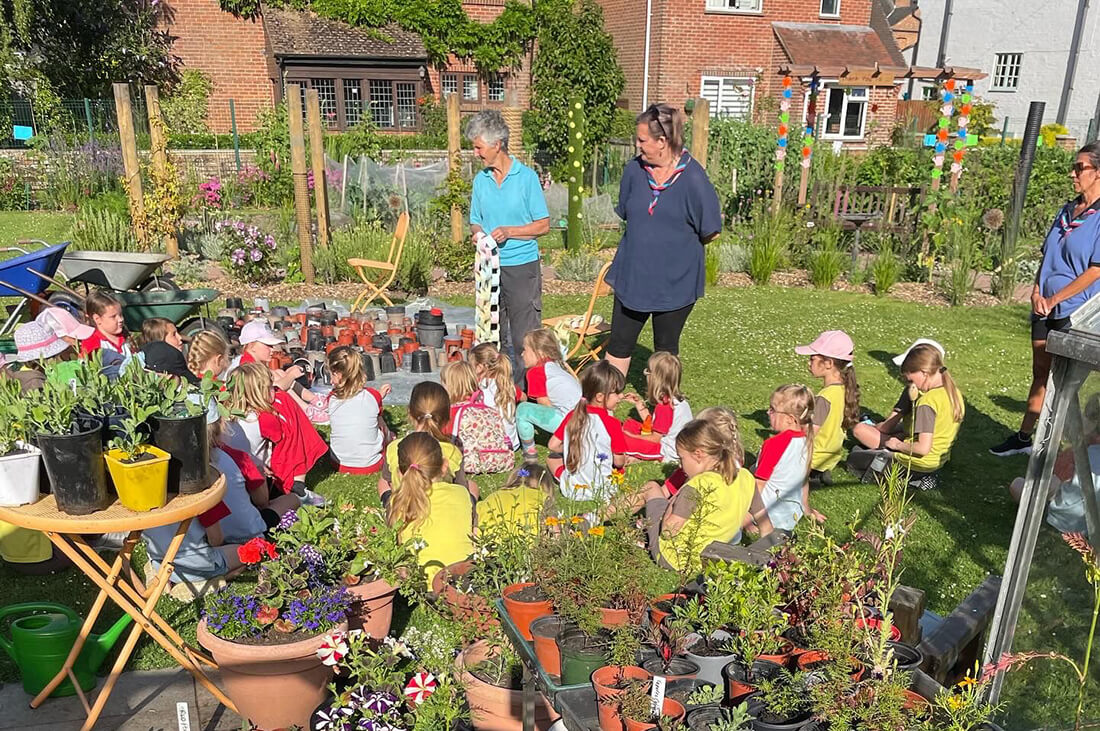 A group of children sit in garden with two adults