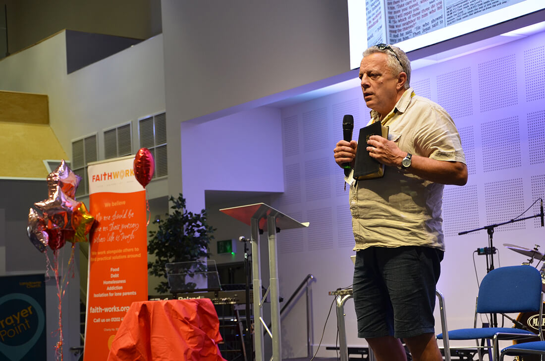 A man holds a Bible and talks into a microphone