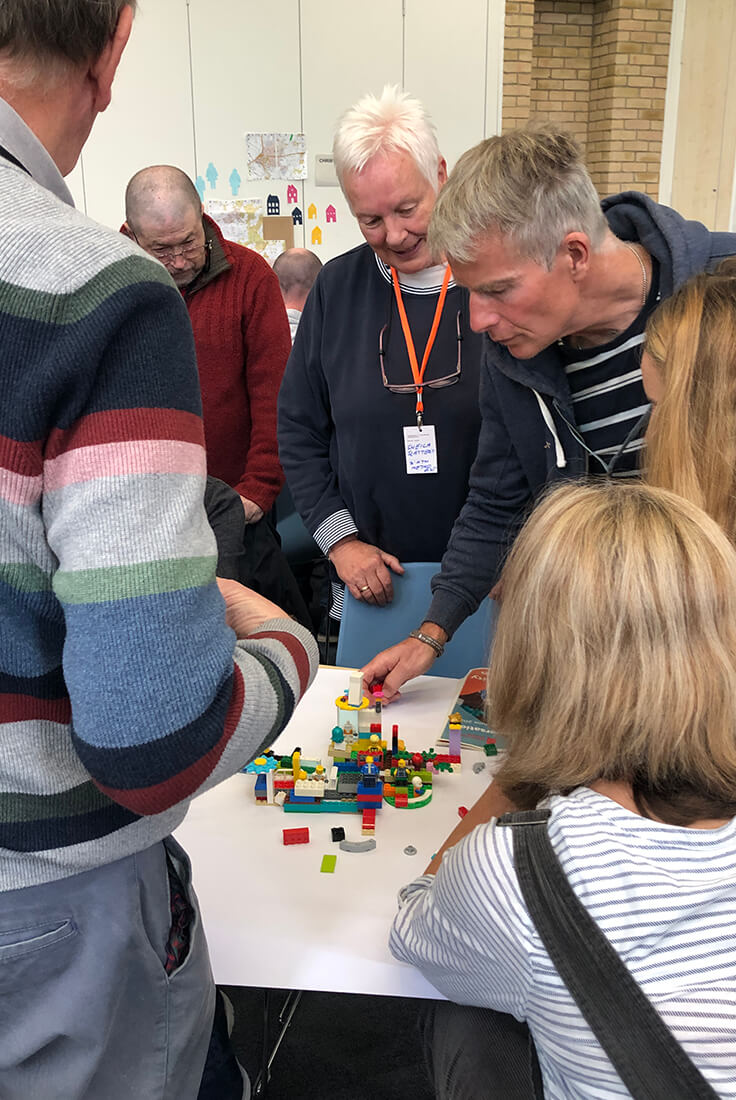 A group of people gather around a table to build a lego model