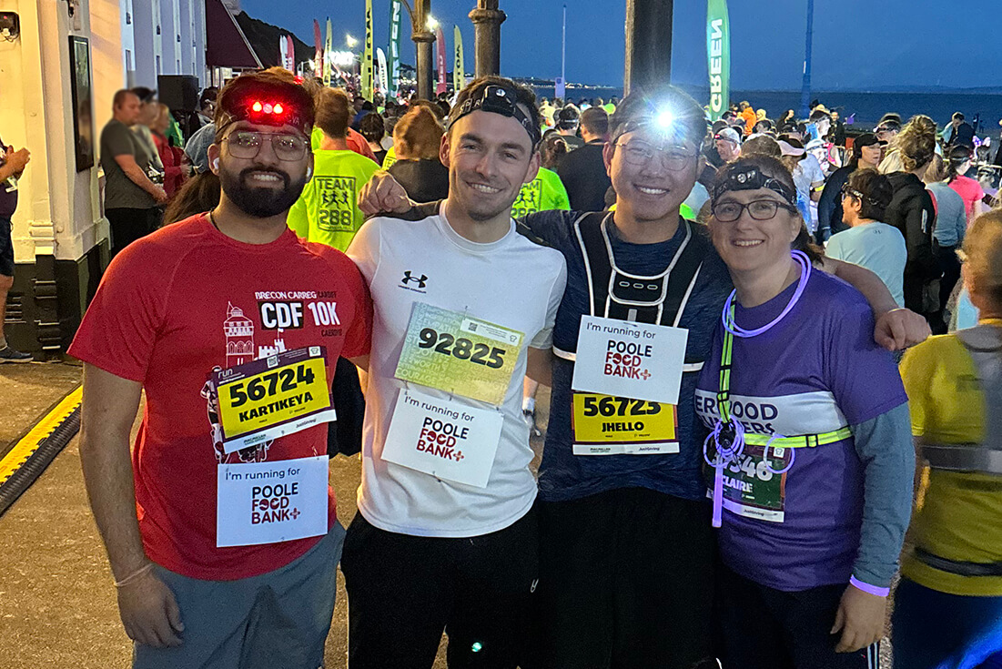 A group of runners with head torches stand smiling at the camera