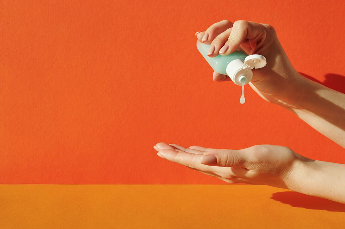 A close up of a pair of hands squeezing soap from a bottle